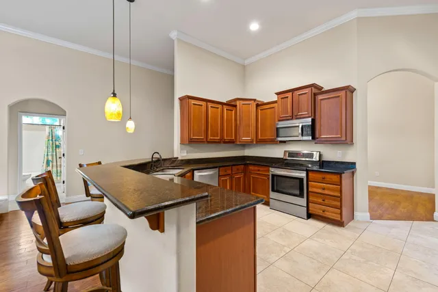 a kitchen with granite countertop a stove a sink and a refrigerator