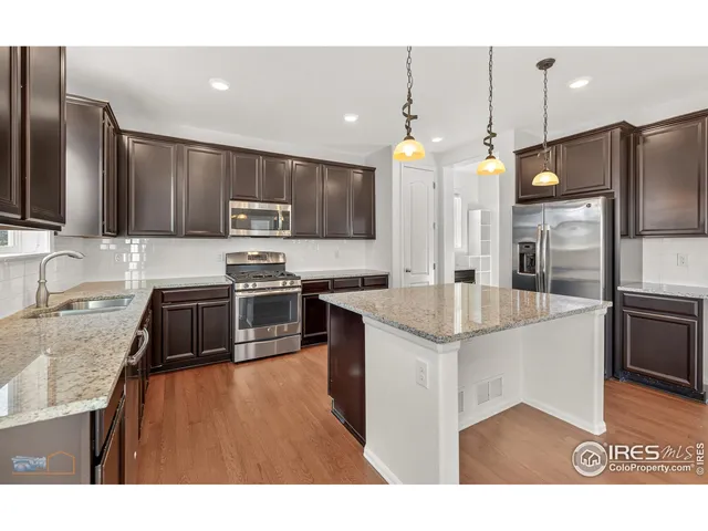 a kitchen with stainless steel appliances granite countertop a sink a stove and a refrigerator