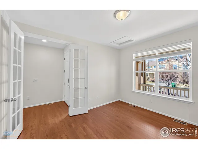a view of an empty room with a window and wooden floor