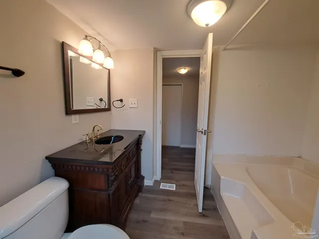a bathroom with a granite countertop sink a mirror and a bathtub