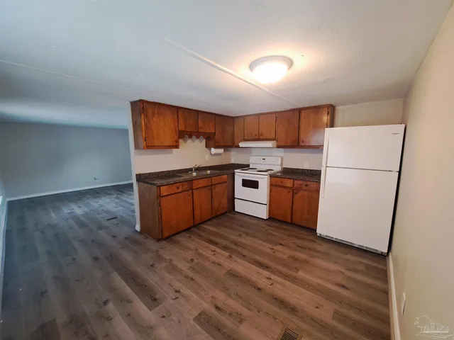 a kitchen with wooden floors and white stainless steel appliances