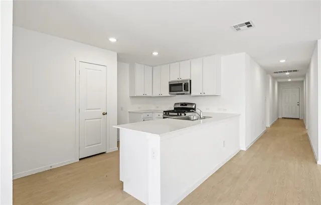 a kitchen with a refrigerator a stove top oven and white cabinets