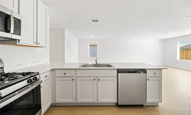 a kitchen with granite countertop a sink cabinets and stainless steel appliances