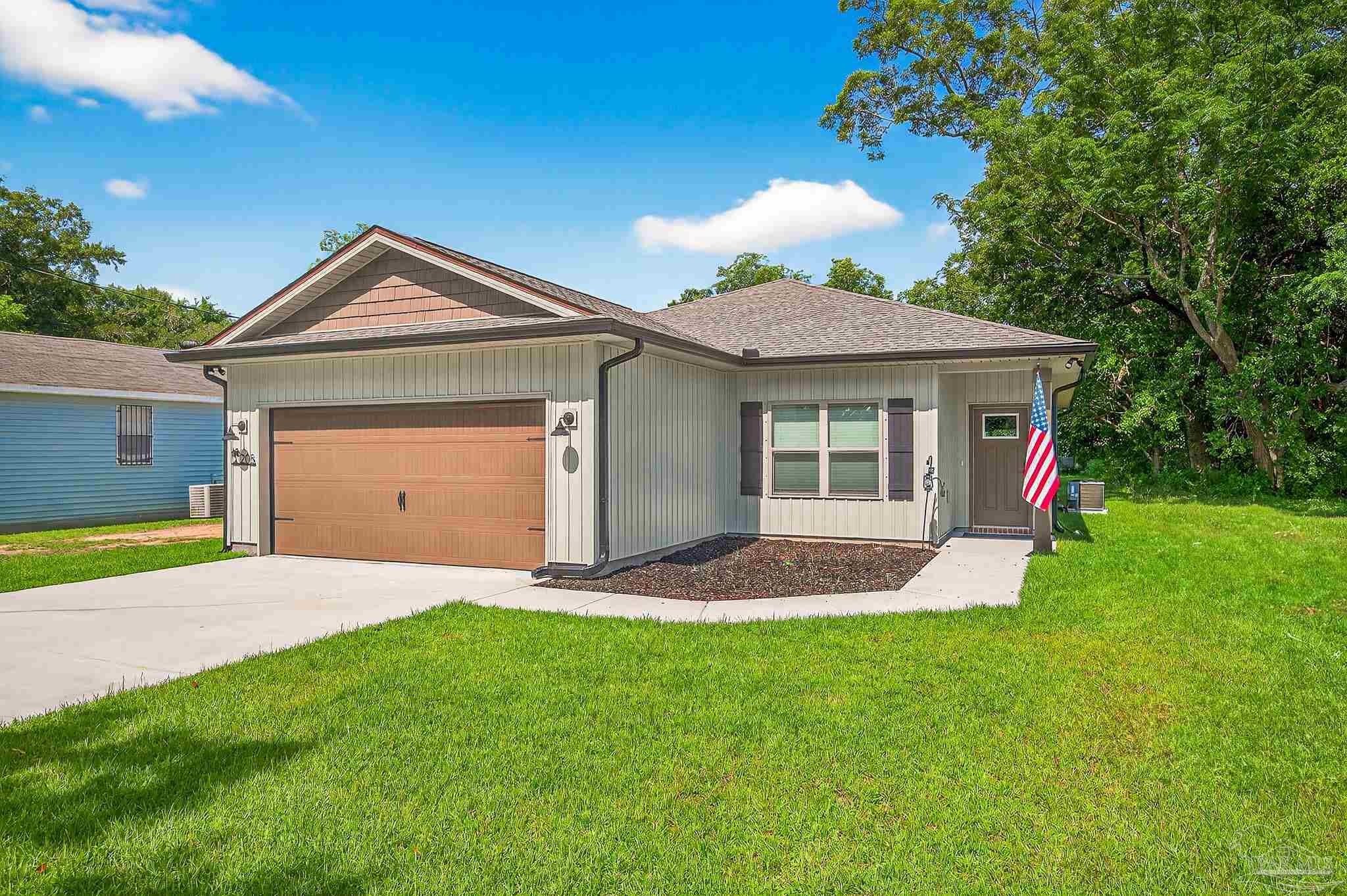 205 Webb Street Cantonment, FL 32533 - Photo 1 of 49 a front view of a house with a yard and garage