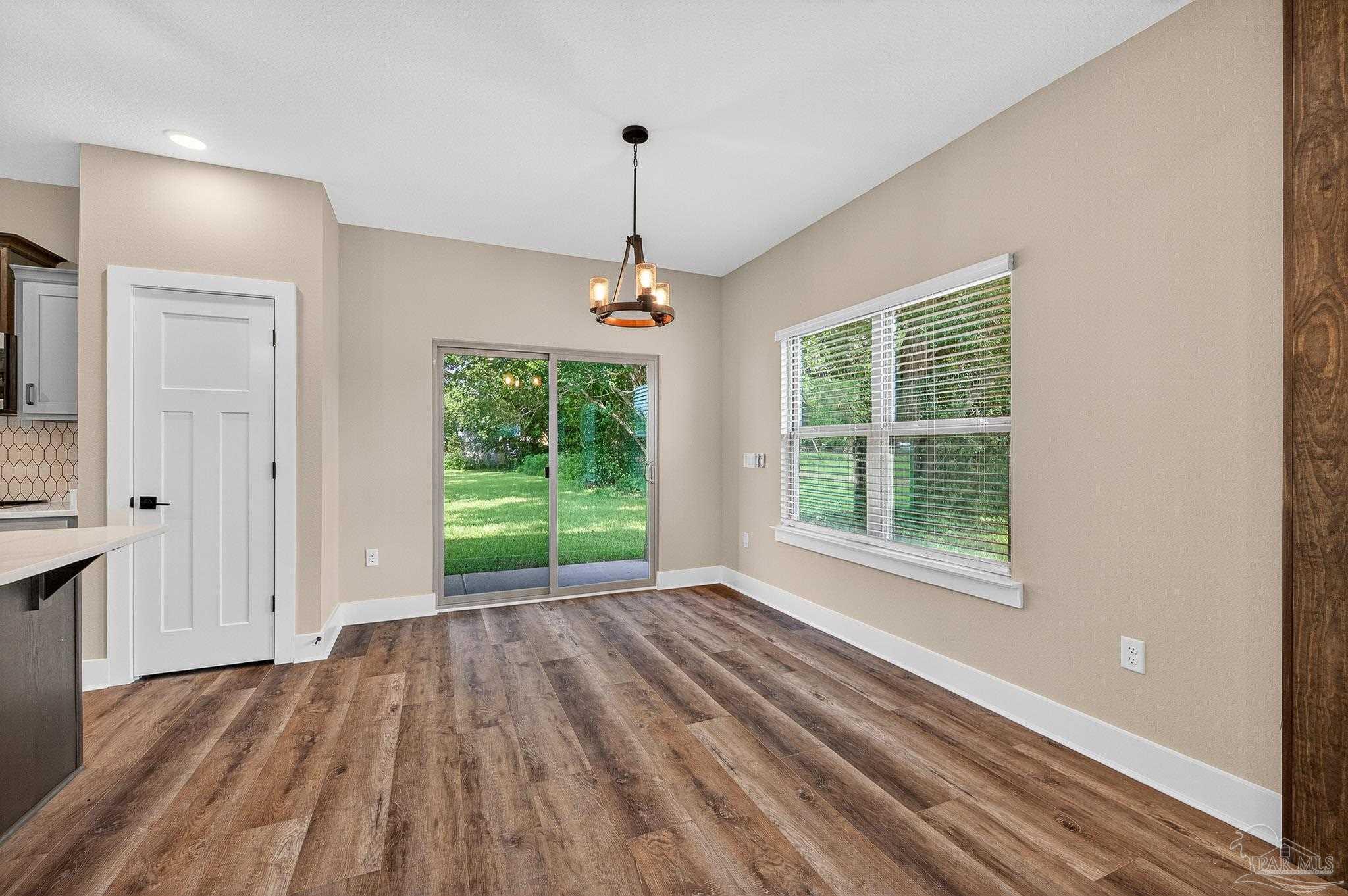 205 Webb Street Cantonment, FL 32533 - Photo 10 of 49 a view of an empty room with wooden floor fridge and a window