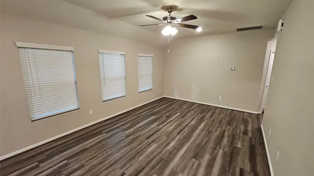 a view of empty room with wooden floor and fan