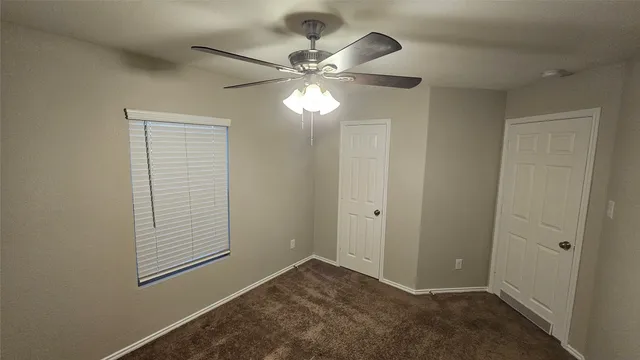 an empty room with windows and fan