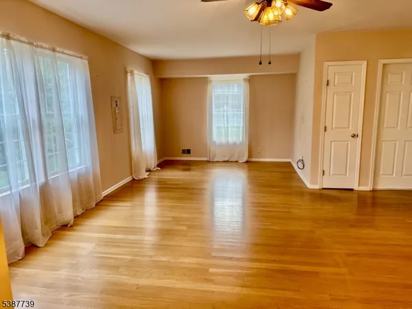 a view of an empty room with window and wooden floor