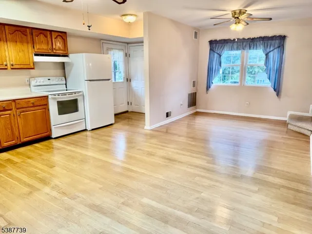 a kitchen with a refrigerator a stove top oven a counter space and wooden floor