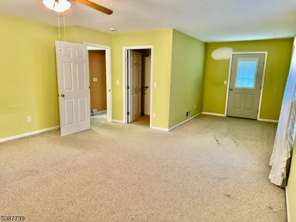 an empty room with closet and a chandelier fan