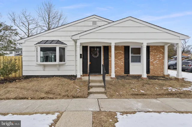 a view of a white house with a large tree in front of it