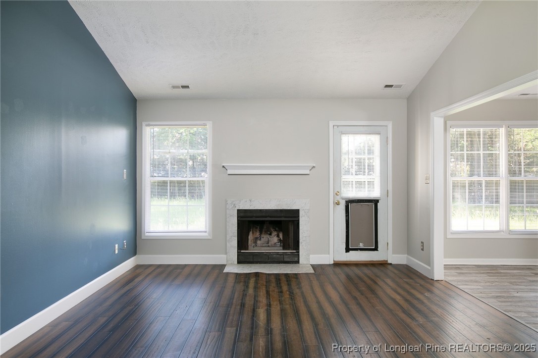 163 Independence Drive Raeford, NC 28376 - Photo 2 of 10 an empty room with wooden floor fireplace and windows