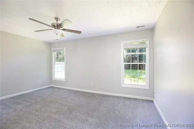an empty room with windows and fan