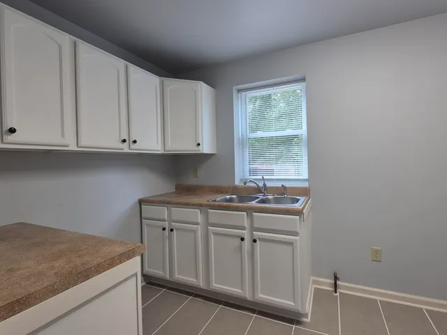a kitchen with stainless steel appliances granite countertop white cabinets and window