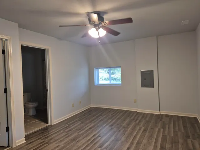 a view of an empty room with wooden floor and a ceiling fan