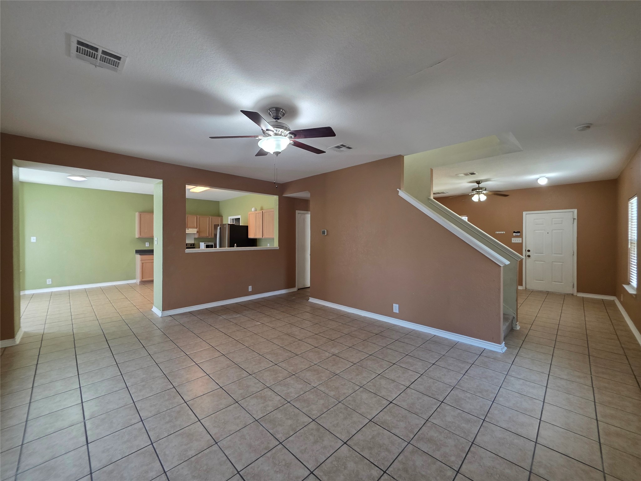 189 Ruidoso Road Kyle, TX 78640 - Photo 8 of 31 A spacious living area with tile flooring and a ceiling fan offers an inviting atmosphere, with a clear view into the adjacent kitchen.