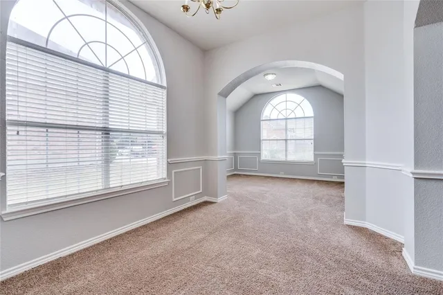 an empty room with windows closet and chandelier fan