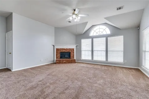 an empty room with windows and fireplace
