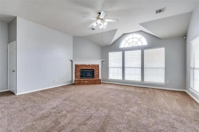 an empty room with windows and fireplace
