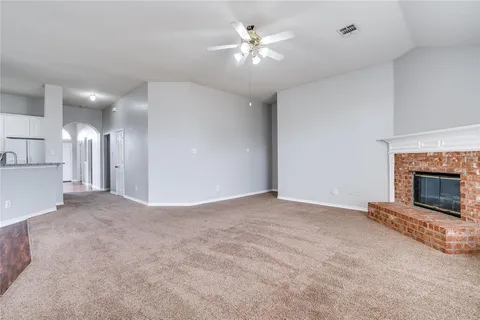 a view of a room a ceiling fan a fireplace and entryway