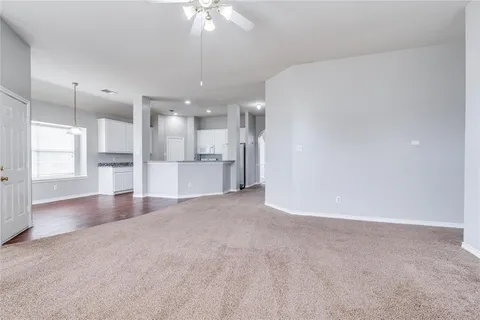 an empty room with a kitchen and a chandelier