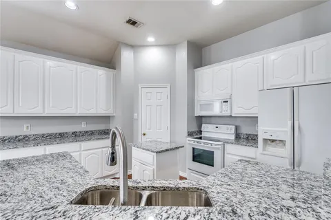 a kitchen with stainless steel appliances granite countertop a sink a stove and a refrigerator