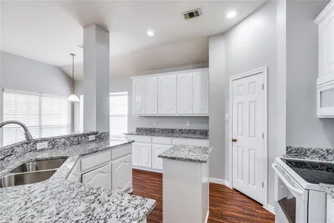a kitchen with granite countertop a sink stove and cabinets