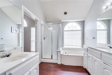 a bathroom with a granite countertop tub sink a window and mirror