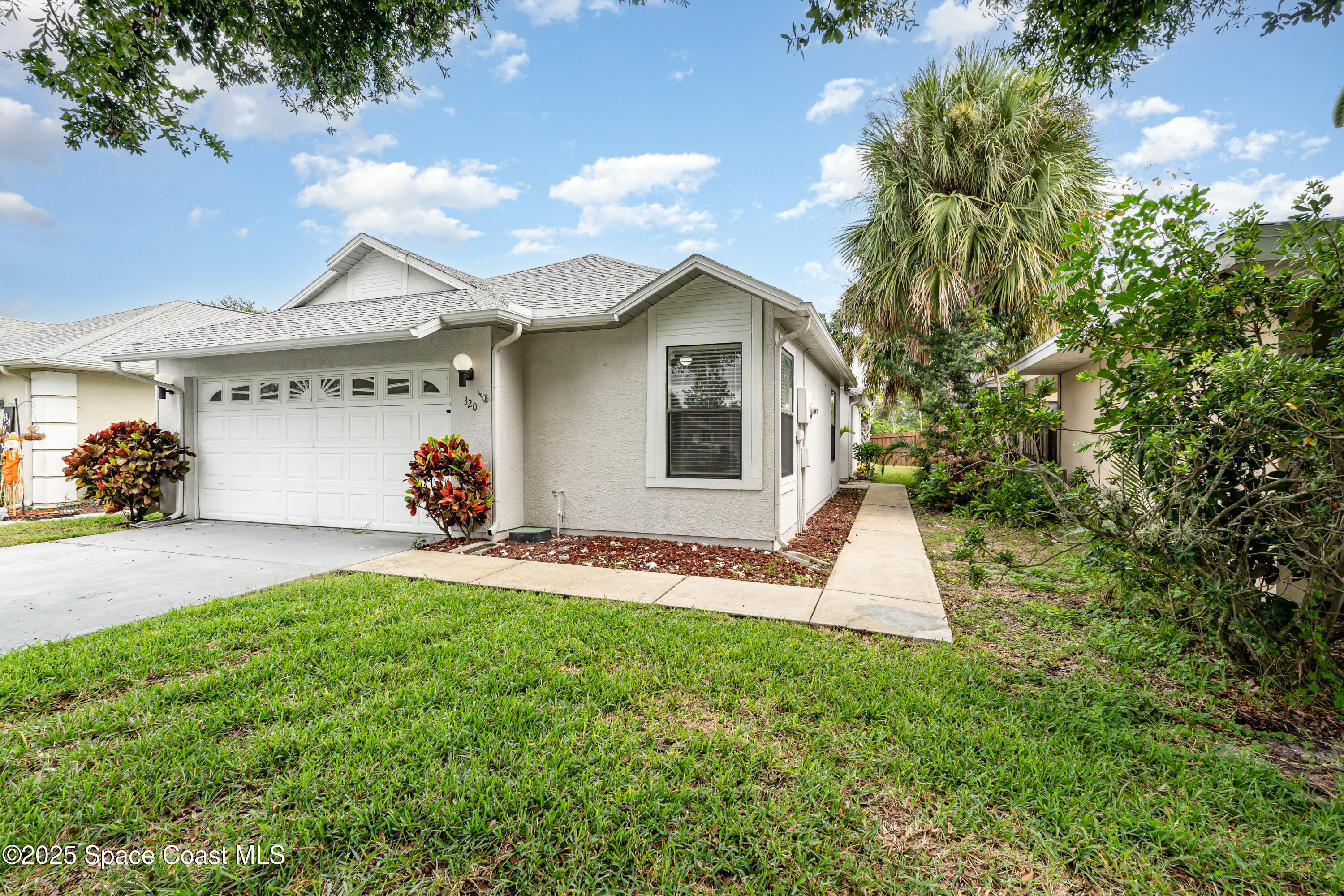 320 Myrtlewood Road Melbourne, FL 32940 - Photo 2 of 18 a front view of a house with a yard and garage