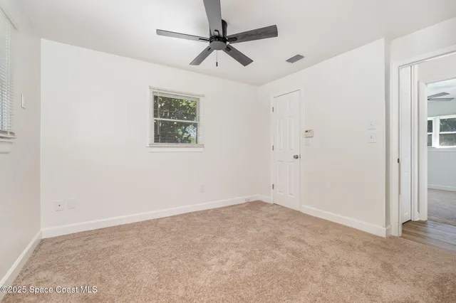 an empty room with a window and a fan
