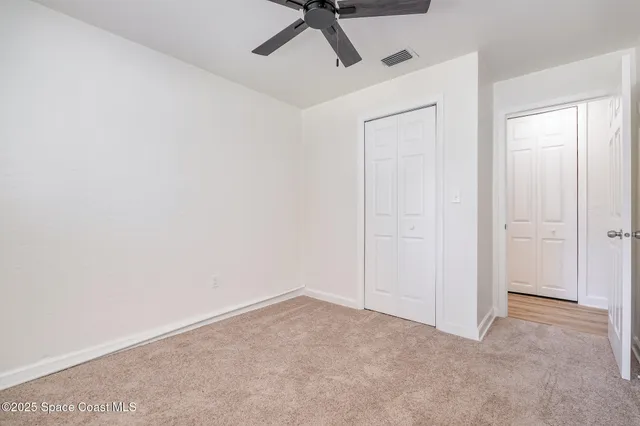 an empty room with a ceiling fan and carpet