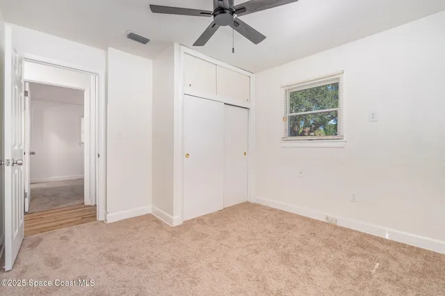 a view of empty room with window and ceiling fan