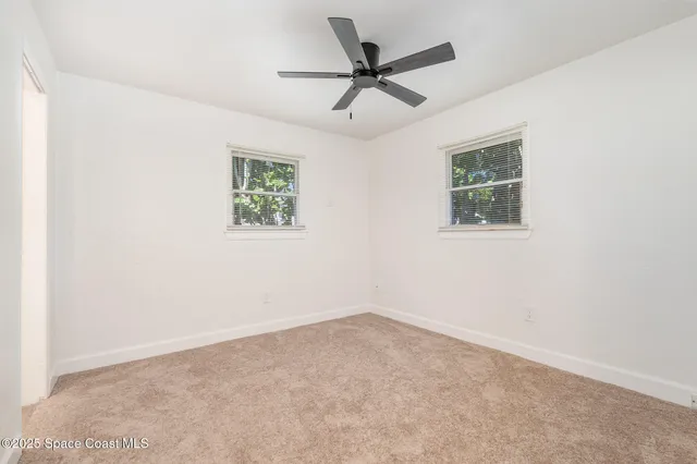 an empty room with a window and a fan