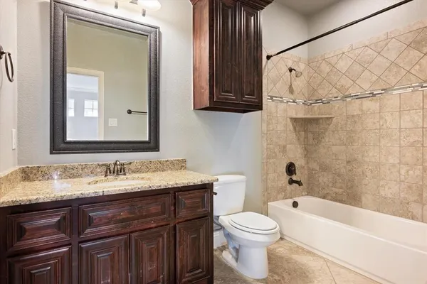 a bathroom with a granite countertop sink a toilet and bathtub