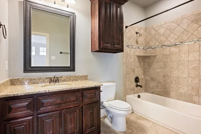 a bathroom with a granite countertop sink a toilet and bathtub