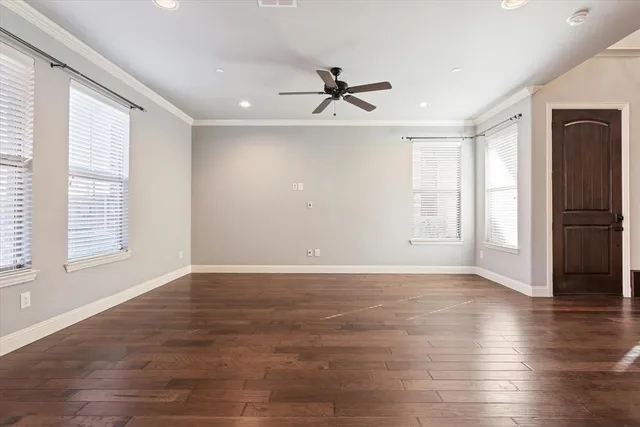 an empty room with wooden floor a ceiling fan and windows