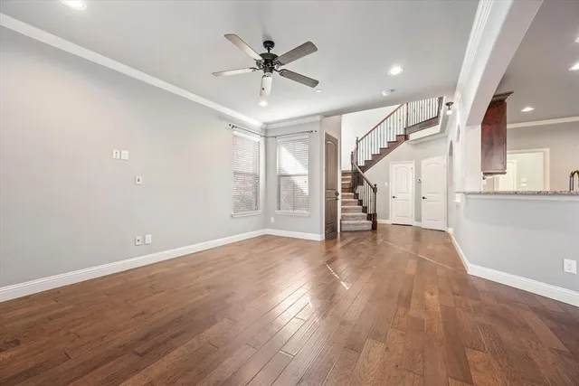 a view of an empty room with wooden floor and a ceiling fan