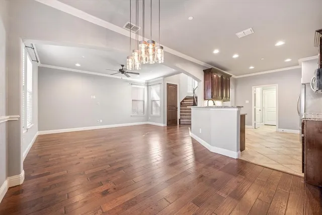 a view of a hallway with wooden floor and a kitchen