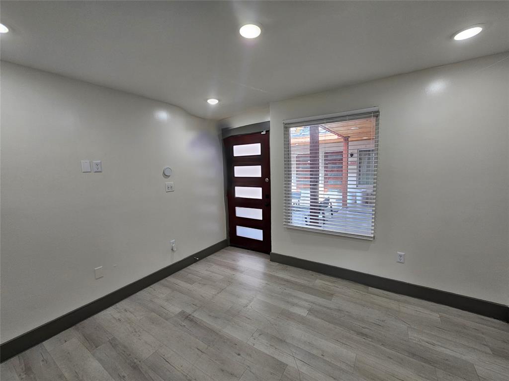 4806 Virginia Avenue, Unit 108 Dallas, TX 75204 - Photo 3 of 9 an empty room with wooden floor and windows