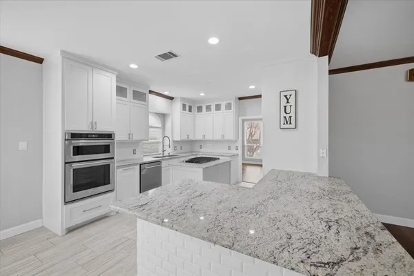 a kitchen with stainless steel appliances kitchen island granite countertop a stove and a sink