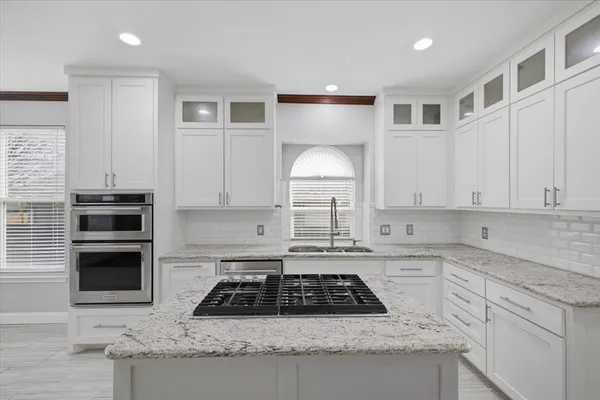 a kitchen with granite countertop a sink a stove and cabinets