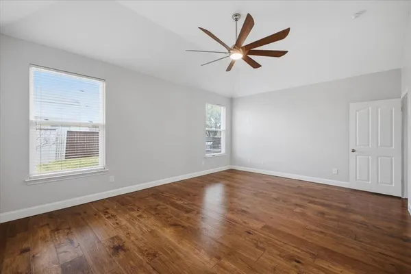 a view of a big room with wooden floor and windows