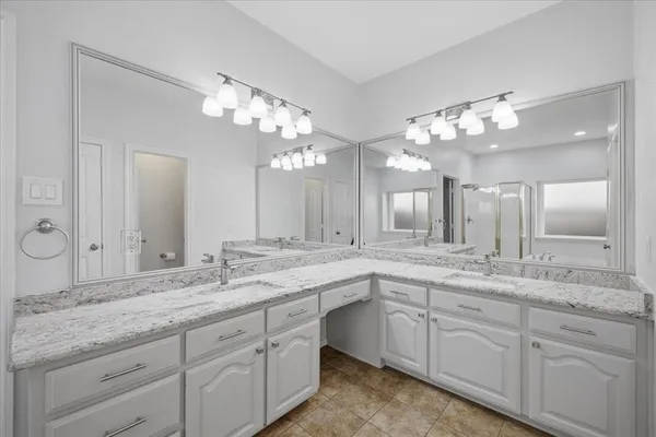 a bathroom with double vanity sinks a vanity a lamp and a mirror