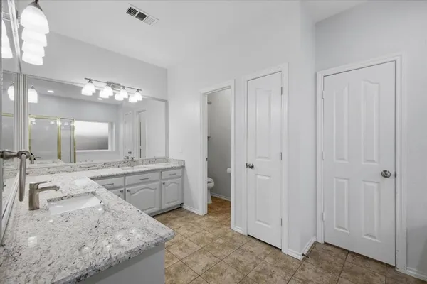 a spacious bathroom with a granite countertop sink a mirror and a shower