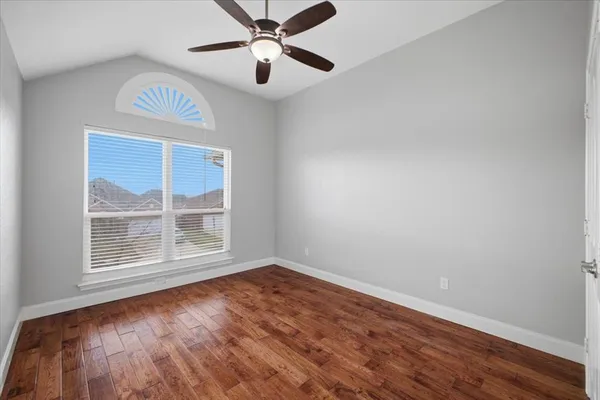 an empty room with wooden floor fan and windows