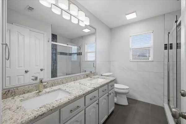 a bathroom with a granite countertop sink a toilet and a mirror