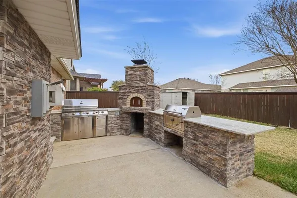 a view of a house with a barbeque and wooden fence