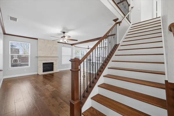 a view of a livingroom with wooden floor a ceiling fan and staircase