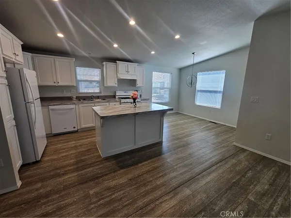 a kitchen with stainless steel appliances granite countertop a sink a stove a refrigerator cabinets and wooden floor