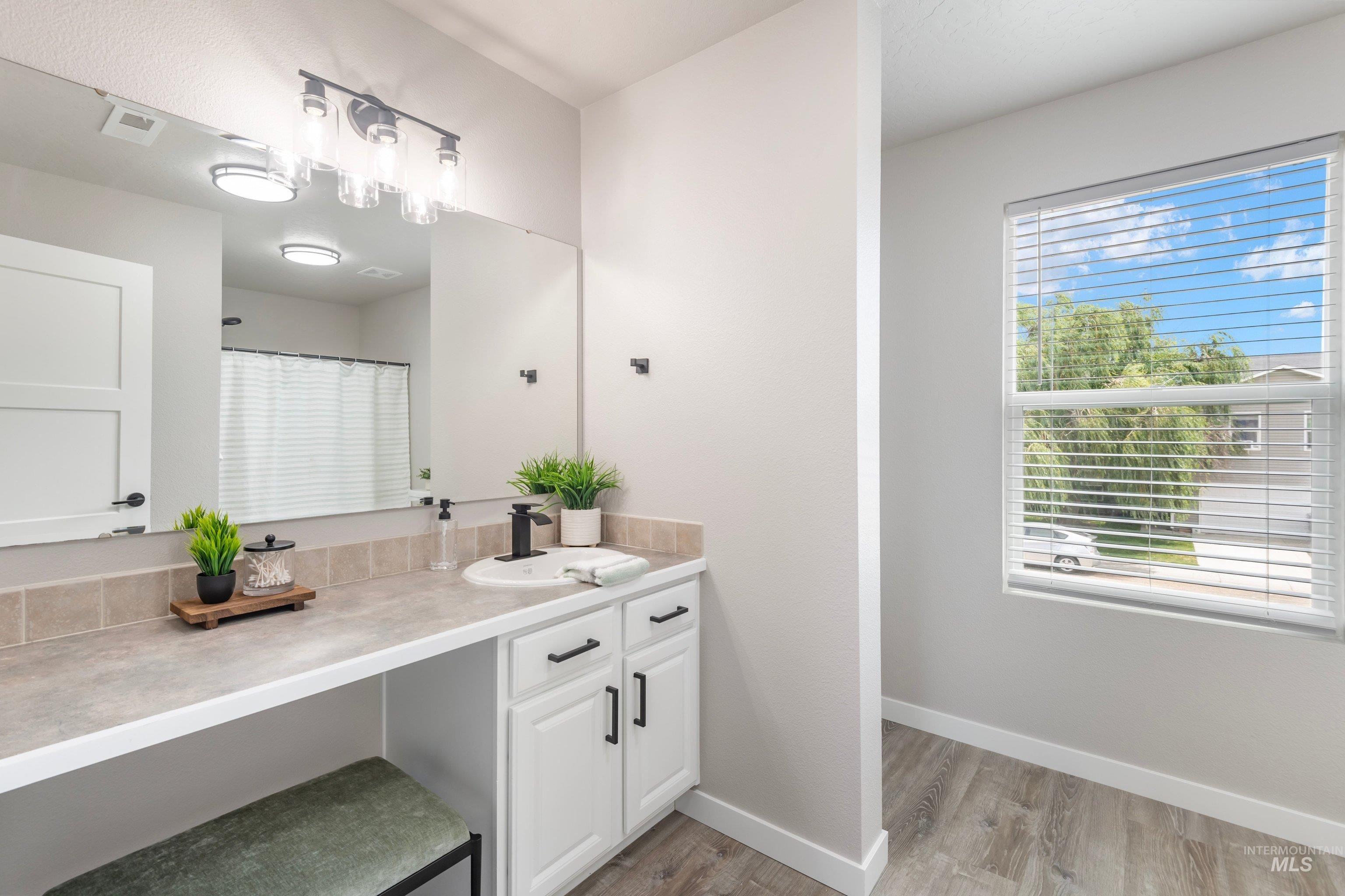 16759 Abram Avenue Caldwell, ID 83607 - Photo 22 of 33 Bathroom vanity with an integrated sink, black faucet, and white cabinetry featuring black hardware